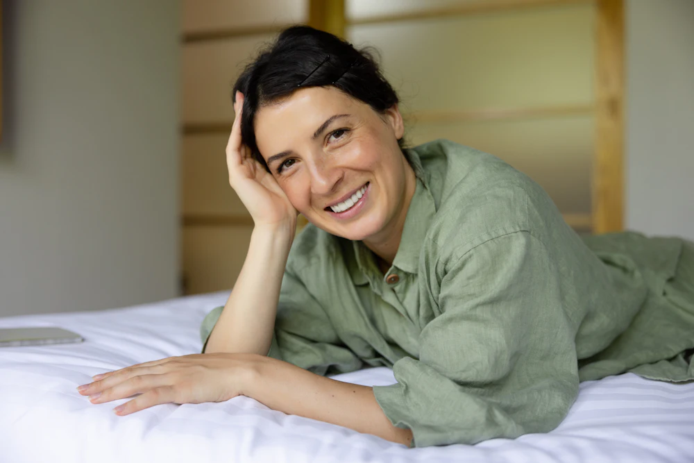A rested woman smiling in bed in the morning