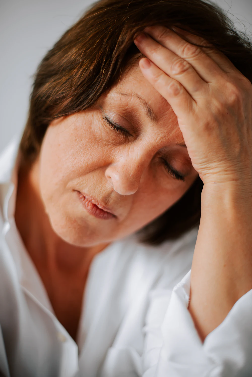 A tired woman in her fifties holding her forehead