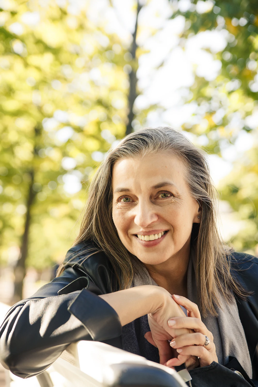 A confident, smiling woman in her fifties outdoors